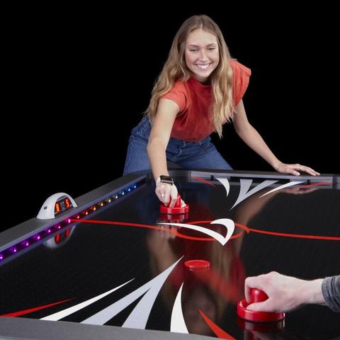 girl playing a game on the Fat Cat Volt LED Light-Up Air Hockey Table